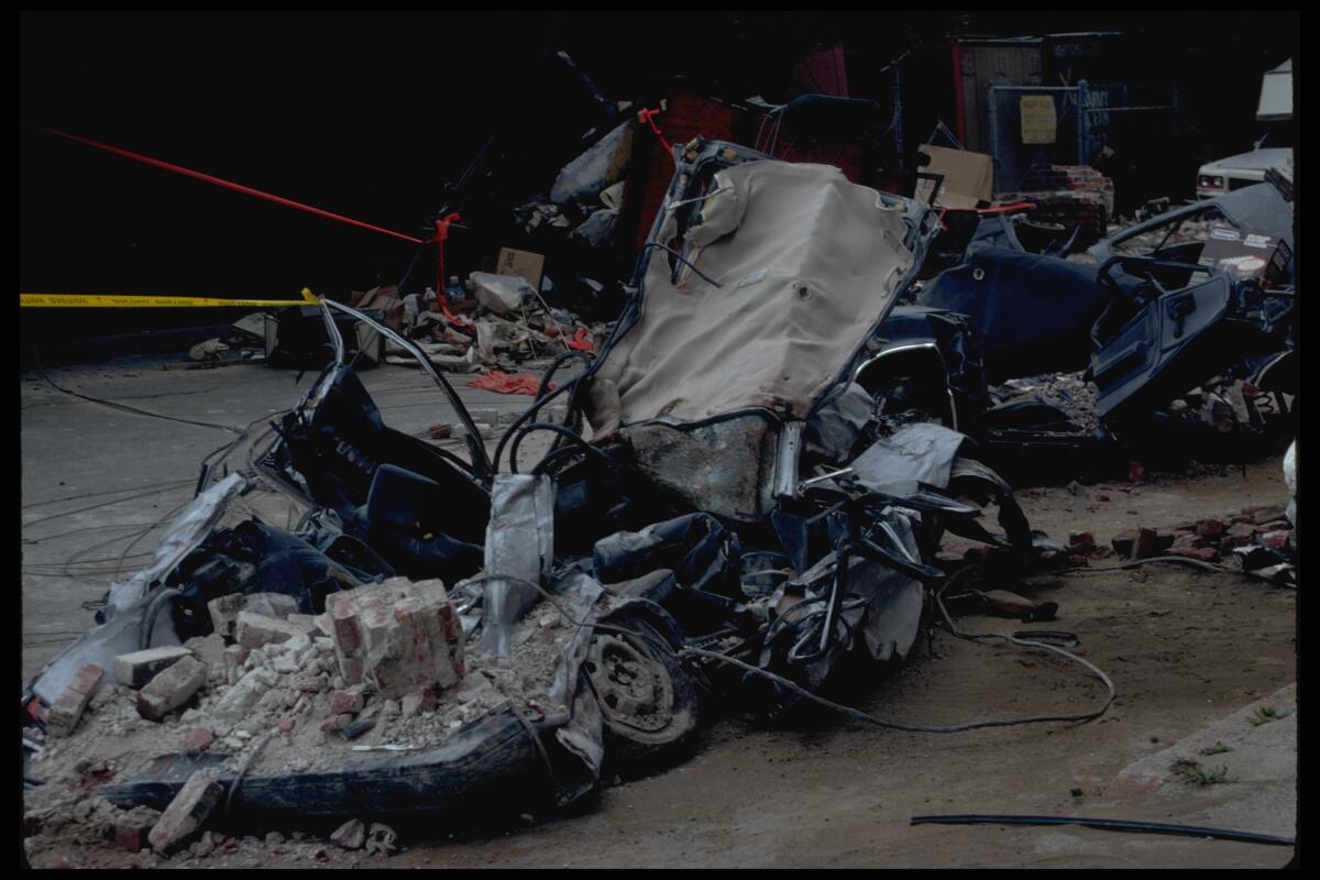 The wrecked remains of a car crushed by pieces of a brick building that partially collapsed in an earthquake.