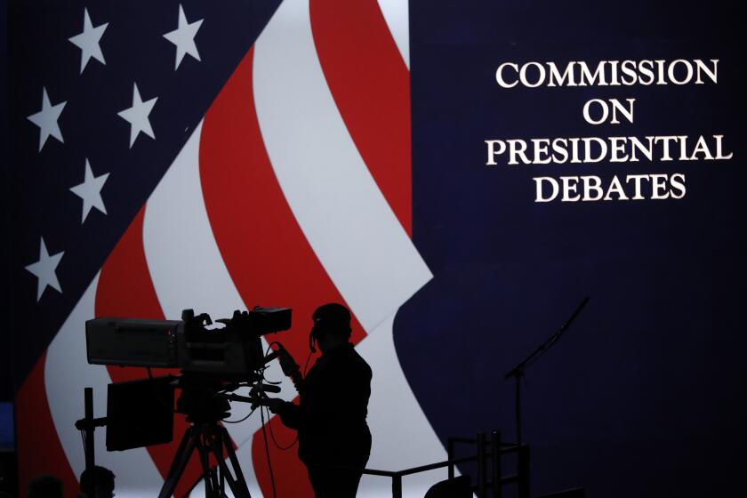 FILE - A cameraman is silhouetted against an an American flag during preparations for the presidential debate at Hofstra University in Hempstead, N.Y., Sept. 25, 2016. The nonpartisan Commission on Presidential Debates, which has planned presidential faceoffs in every election since 1988, has an uncertain future after President Joe Biden and former President Donald Trump struck an agreement to meet on their own. (AP Photo/Mary Altaffer, File)
