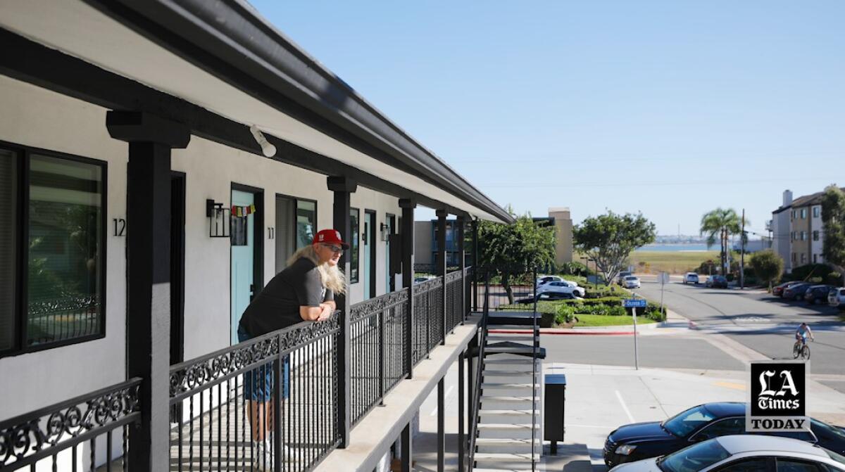 A man looks over a railing at an apartment complex