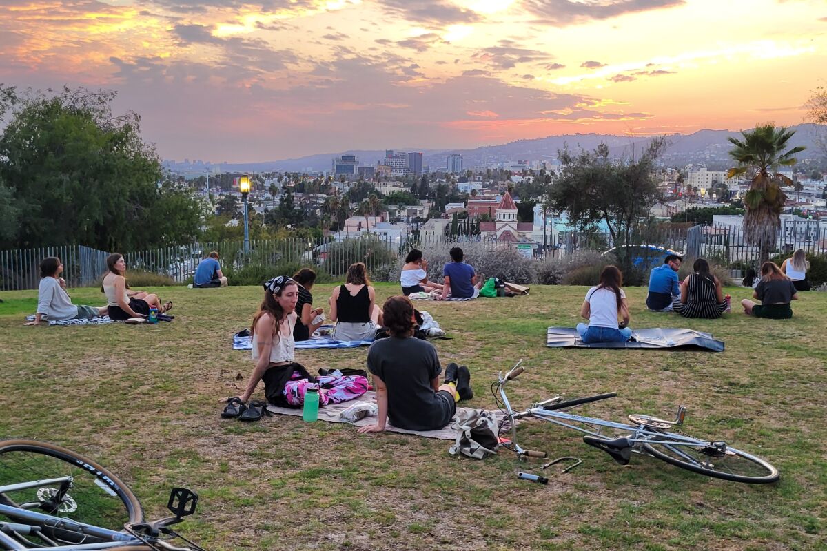 At sunset, people relax on the lawn at Barnsdall Art Park.