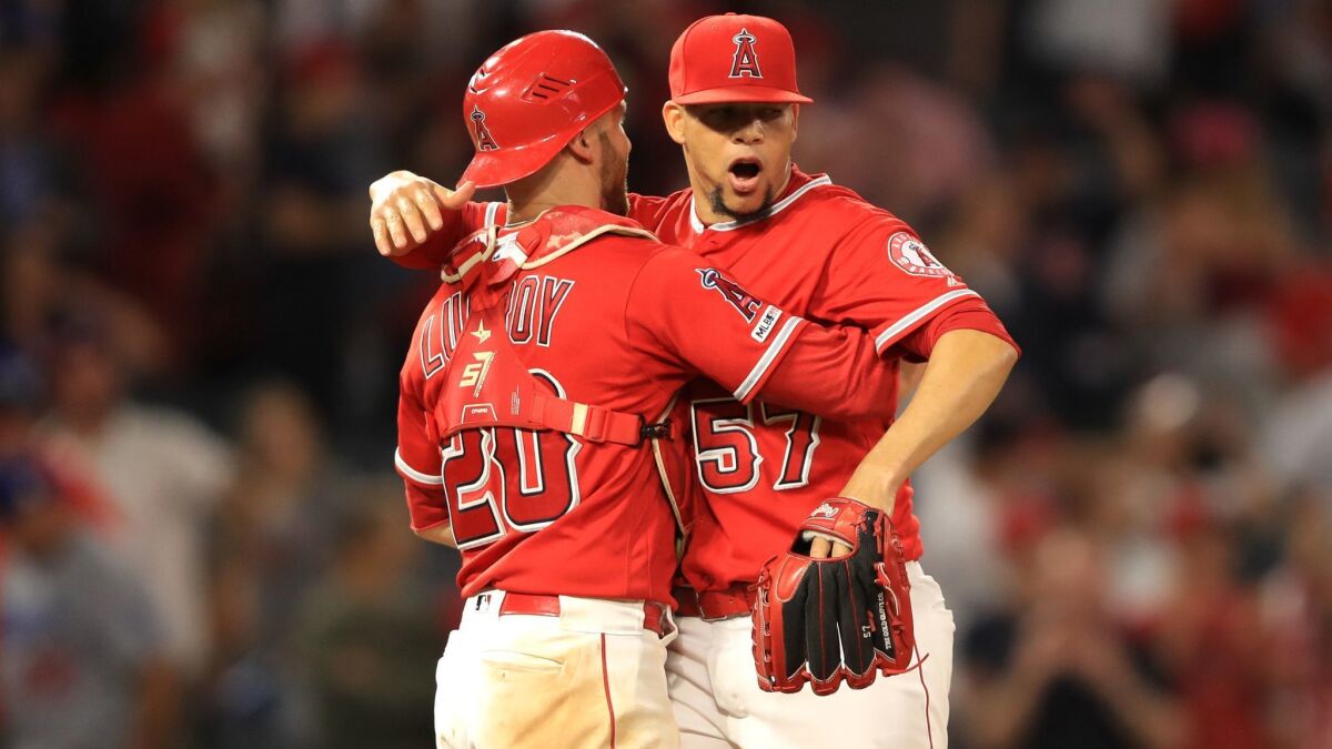 Angels catcher Jonathan Lucroy, left, and pitcher Hansel Robles celebrate after defeating the Dodgers 5-3 at Angel Stadium on Tuesday.