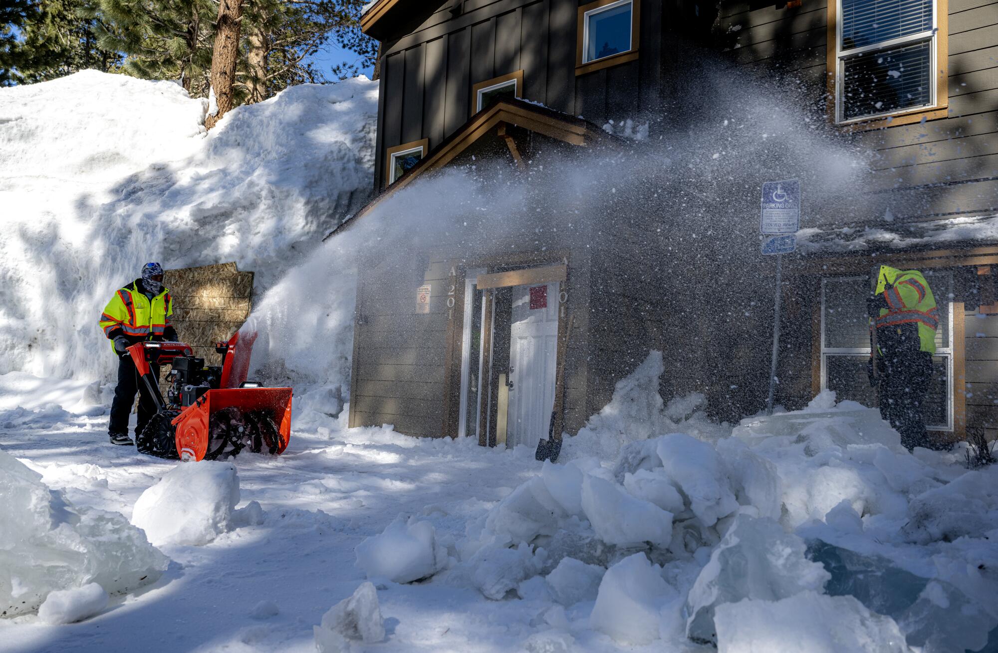 Workers in Mammoth Lakes   clear snow from an apartment building.