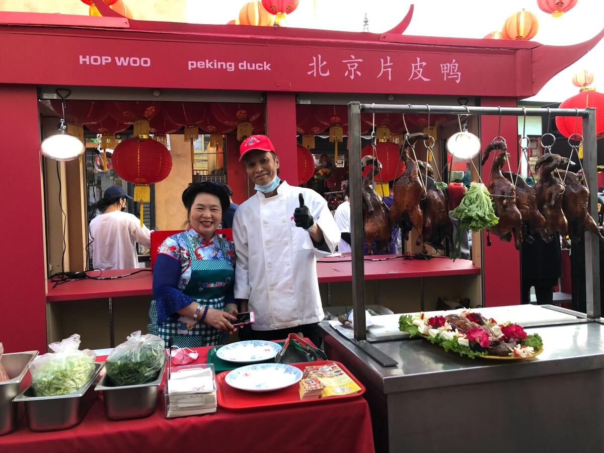 A man and woman pose for a photo outside a restaurant.