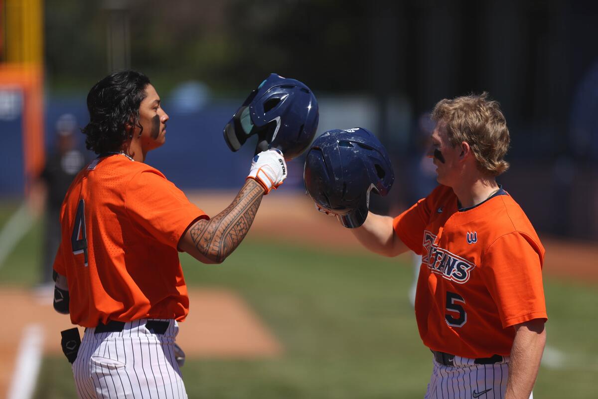 Cal State Fullerton teammates Nate Nankil, left, and Caden Connor tap helmets during a game.
