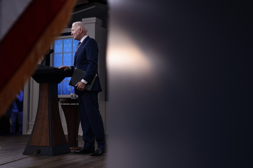 President Biden standing at a lectern, seen from offstage 