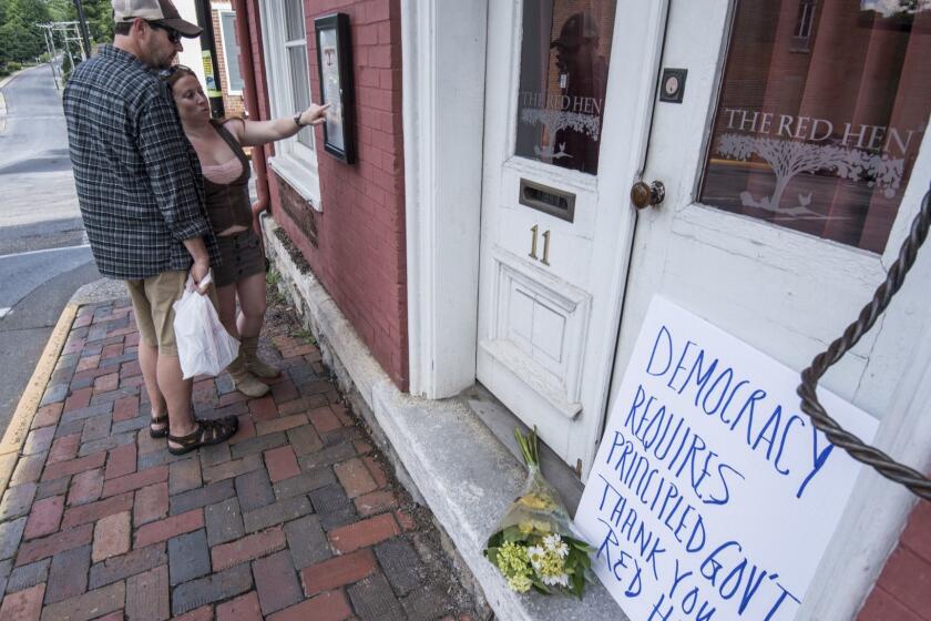 Passersby examine the menu at the Red Hen Restaurant Saturday, June 23, 2018, in Lexington, Va. White House press secretary Sarah Huckabee Sanders said Saturday in a tweet that she was booted from the Virginia restaurant because she works for President Donald Trump. Sanders said she was told by the owner of The Red Hen that she had to "leave because I work for @POTUS and I politely left." (AP Photo/Daniel Lin)/Daily News-Record via AP)