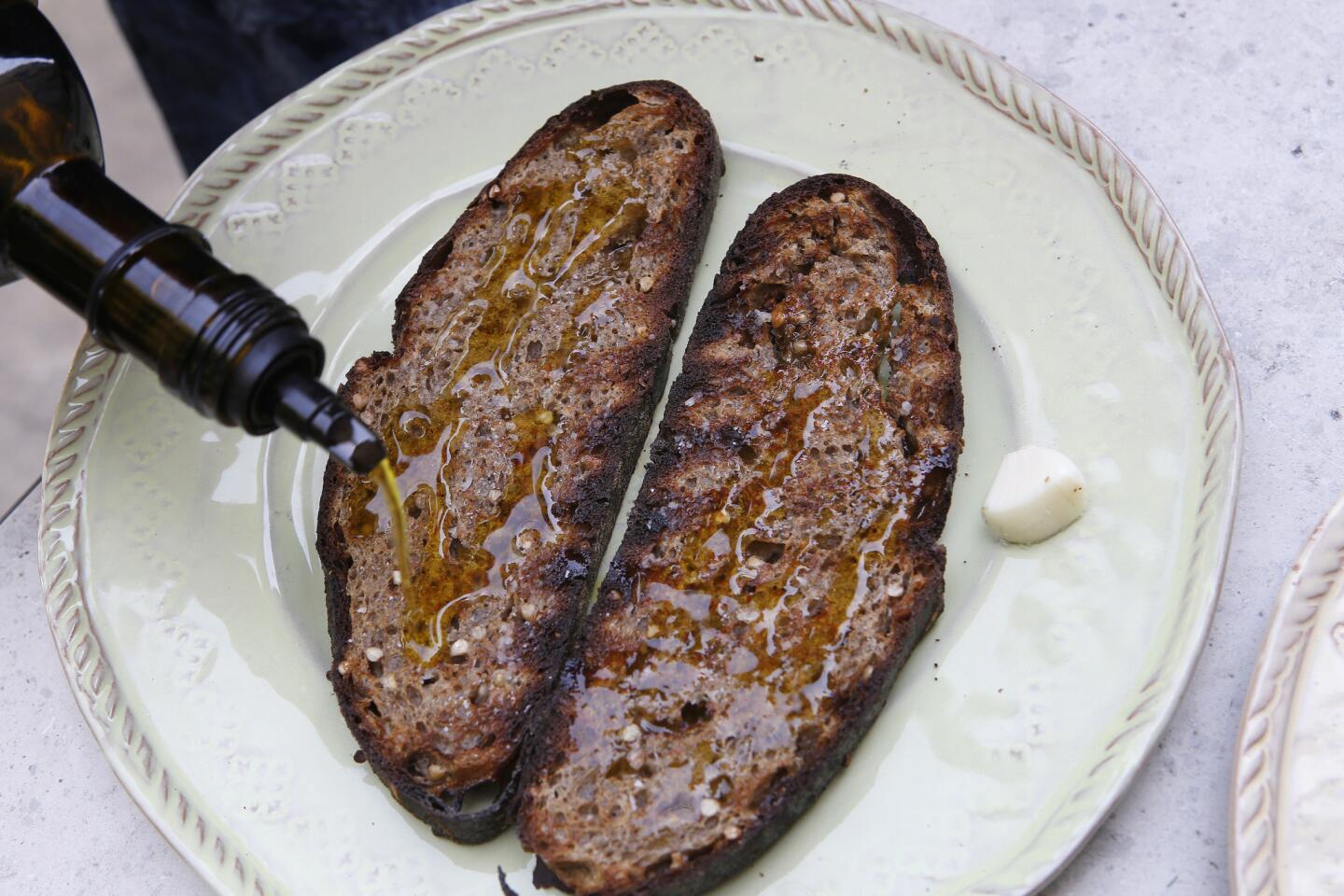 A healthy drizzle of olive oil prepares grilled bread to be the base for bruschetta alla Matalotta.
