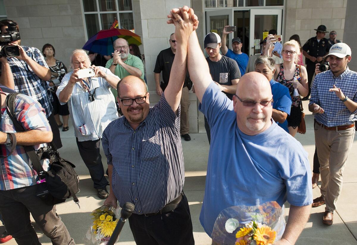 Michael Long, left, and Timothy Long raise their hands after receiving their legal marriage license at the Rowan County Courthouse.