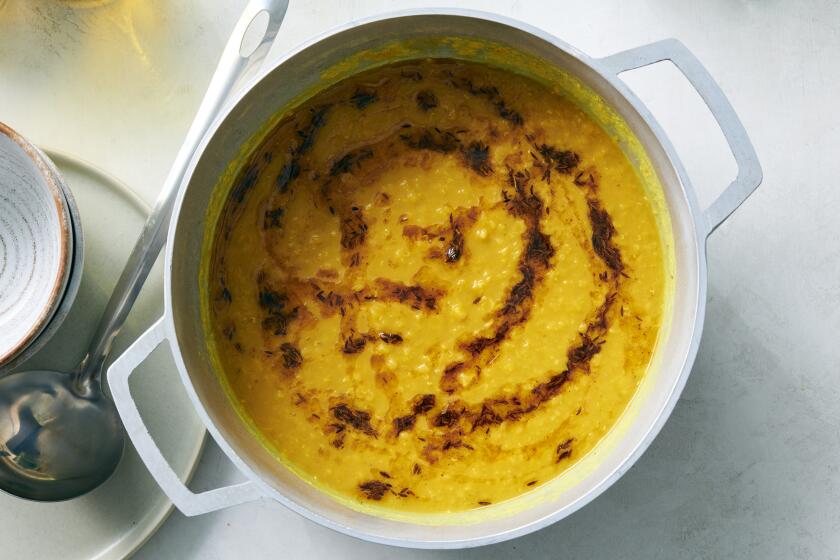 A pot contains dal with a topping.