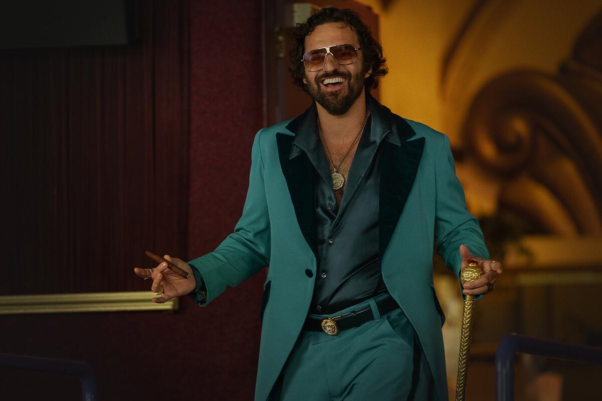 A man wearing a turquoise suit smiles.