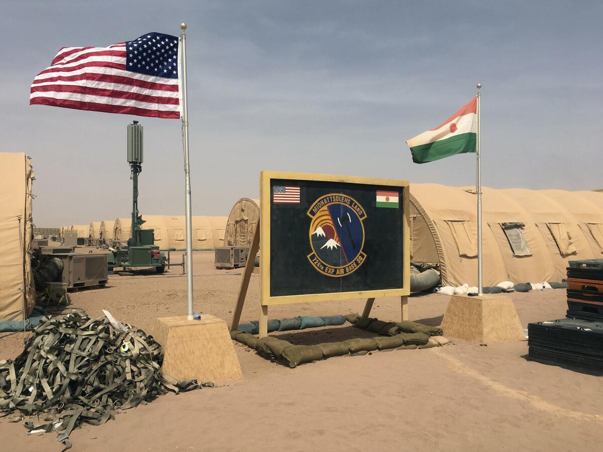 A U.S. and Niger flag are raised side by side near tents.