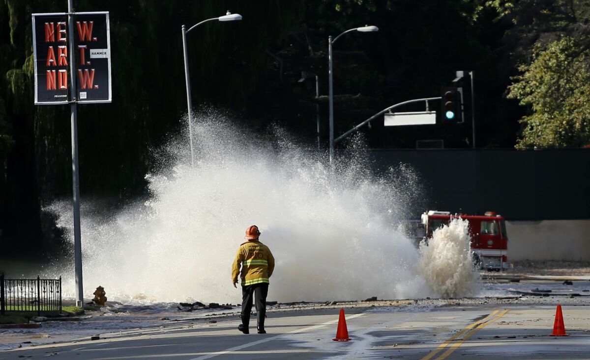 Water gushes from a broken main under Sunset Boulevard near UCLA in 2014. The DWP says it will spend some of the money from the proposed increase in water rates to repair crumbling infrastructure.