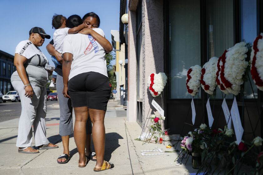 Family members of slain mass shooting victim Thomas "TJ" McNichols, from left, Donna Johnson, aunt, and sisters Jamila and Finesse McNichols, mourn beside a memorial near the scene of the shooting Monday, Aug. 5, 2019, in Dayton, Ohio. (AP Photo/John Minchillo)