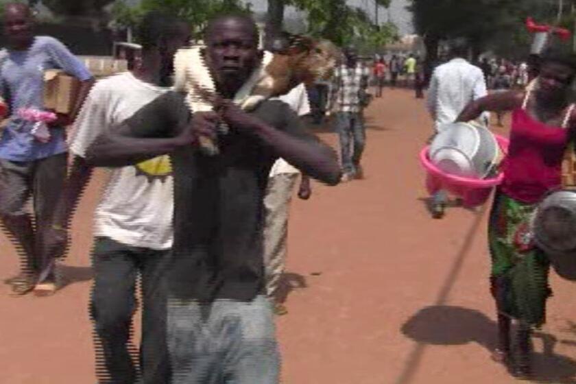 A video grab made on Sunday from an AFPTV video shows suspected looters carrying goods as they walk in a street in Bangui, the capital of the Central African Republic. Looters and armed gangs roamed the streets after rebels seized control of the city and the coup-prone country's president disappeared.
