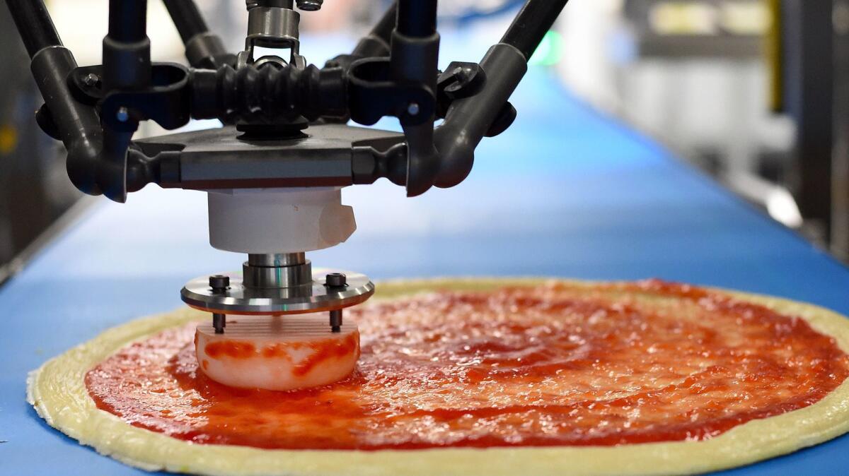 A pizza sauce-spreading delta robot nicknamed "Marta" spreads marinana on a pie at Zume Pizza.
