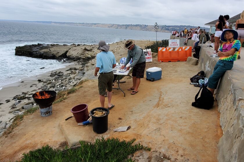 Beach access advocates and body surfers gather for a small barbecue at the trailhead to Boomer Beach, just outside the area of Point La Jolla that is closed to the public.