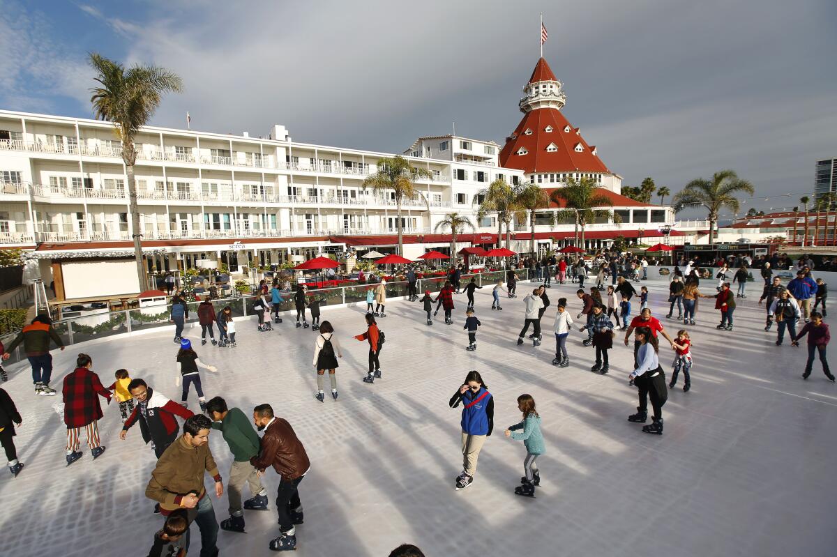 People on a skating rink with a large white multi-story hotel in the background.