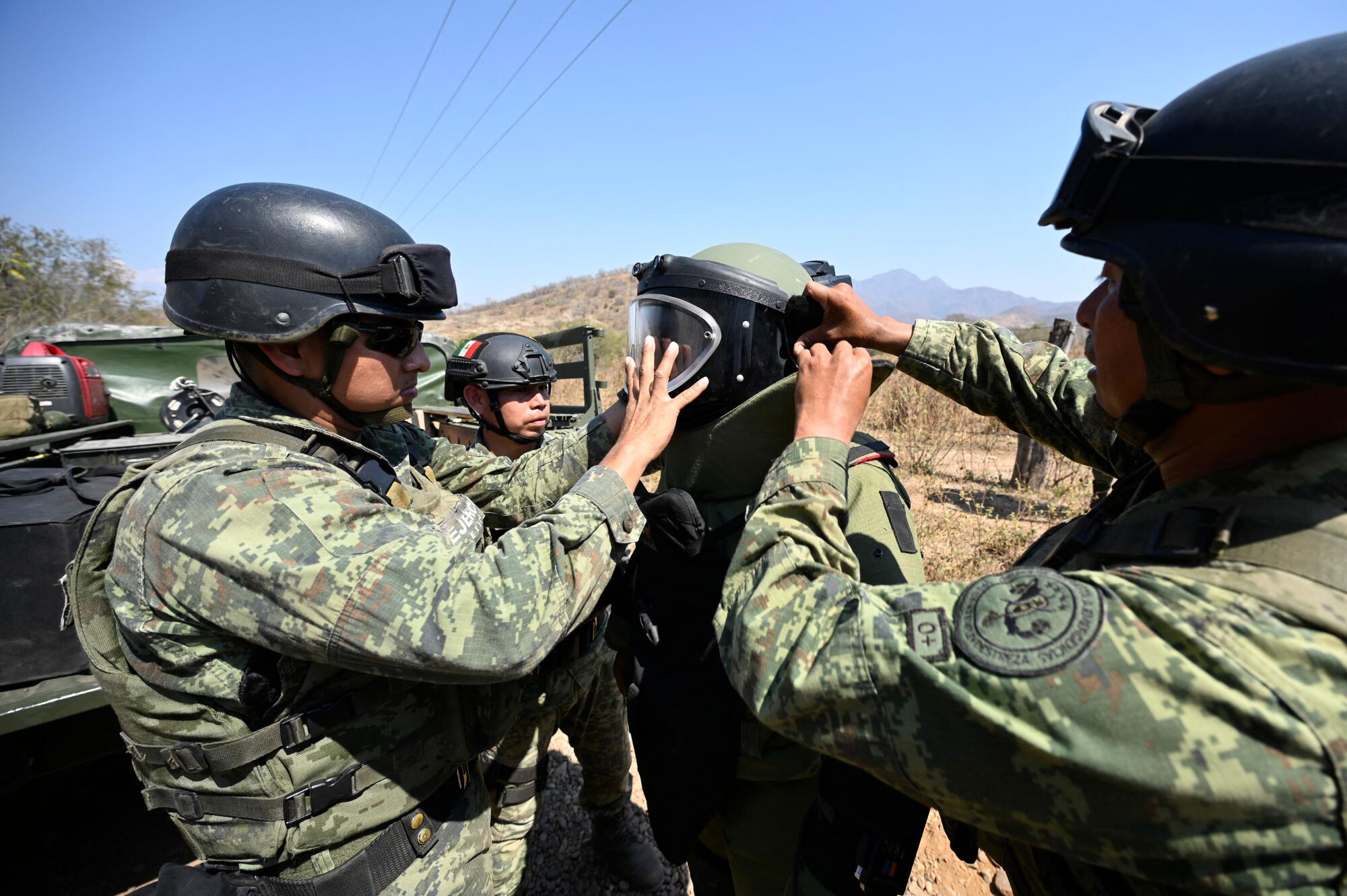 Des soldats aident un autre soldat à enfiler son équipement 