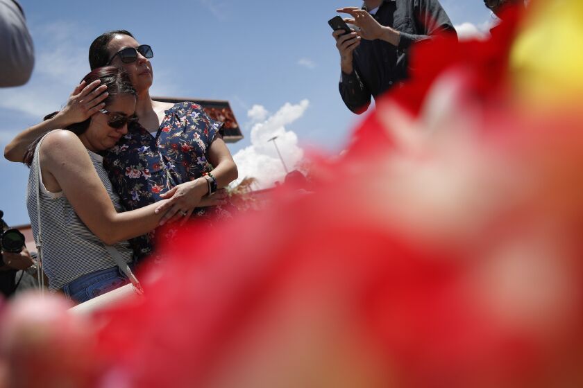 Cynthia Chavez, right, embraces her daughter Mia Chavez as they visit a makeshift memorial at the scene of a mass shooting at a shopping complex Sunday, Aug. 4, 2019, in El Paso, Texas. (AP Photo/John Locher)