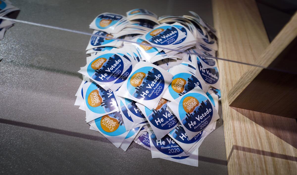 FILE - In this Oct. 30, 2020, file photo stickers printed in Spanish sit on the desk of an election judge to be distributed to voters after they cast their ballots in the atrium of Ball Arena, the home of the NBA's Denver Nuggets and the NHL's Colorado Avalanche in Denver. (AP Photo/David Zalubowski, File)