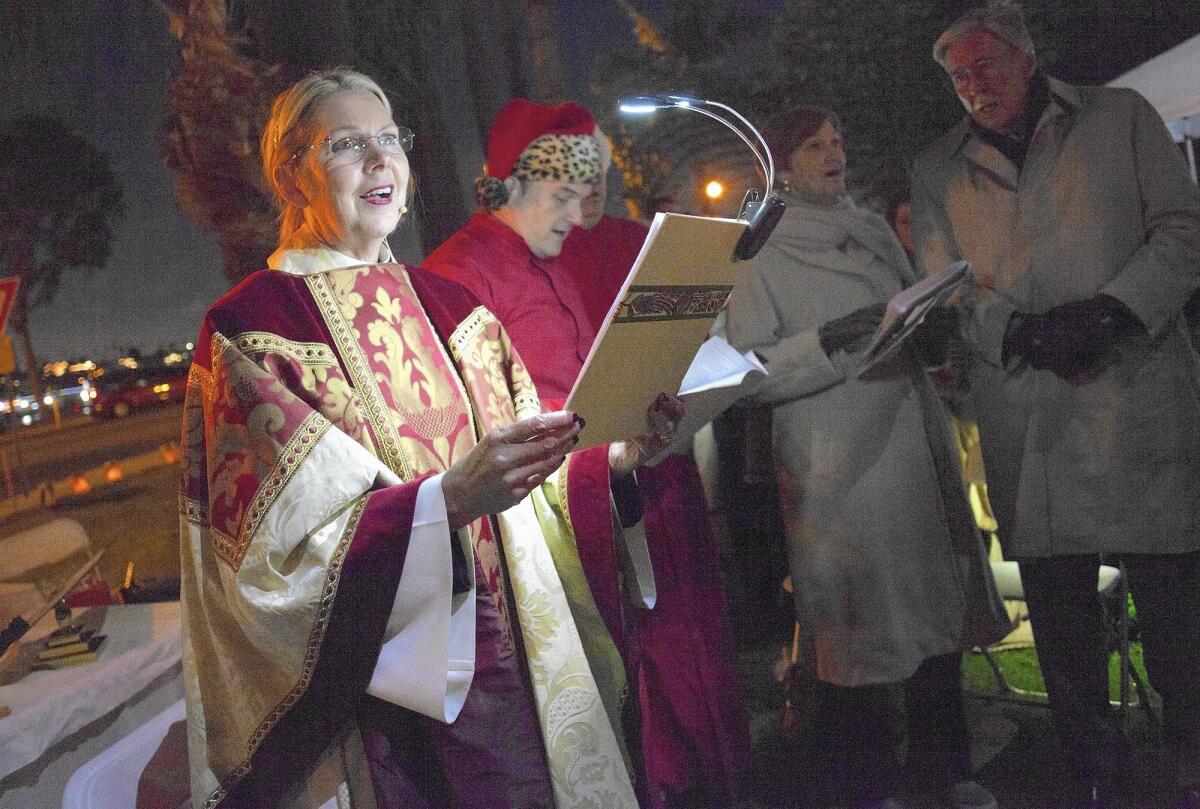 The Rev. Canon Cindy Evans Voorhees sings as she leads St. James the Great Episcopal Church members in an outdoor Christmas Eve celebration at Lido Park in Newport Beach on Thursday.