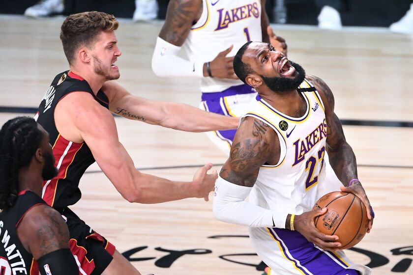 ORLANDO, FLORIDA OCTOBER 4, 2020-Lakers LeBron James is fouled by Heat's Meyers Leonard while scoring a basket in the 1st quarter in Game 3 of the NBA FInals in Orlando Sunday. (Wally Skalij/Los Angeles Times)