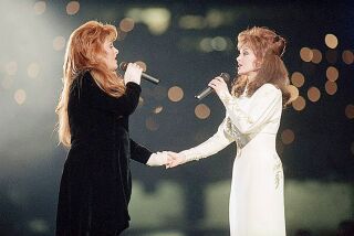 FILE - Wynonna Judd, left, and her mother, Naomi Judd, of The Judds, perform during the halftime show at Super Bowl XXVIII in Atlanta on Jan. 30, 1994. Naomi Judd, the Kentucky-born matriarch of the Grammy-winning duo The Judds and mother of Wynonna and Ashley Judd, has died, her family announced Saturday, April 30, 2022. She was 76. (AP Photo/Eric Draper, File)