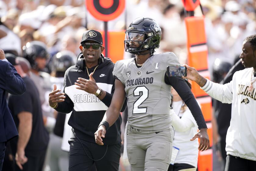 Colorado head coach Deion Sanders, left, talks with his son, quarterback Shedeur Sanders, before the first half of an NCAA college football game against Southern California Saturday, Sept. 30, 2023, in Boulder, Colo. (AP Photo/David Zalubowski)