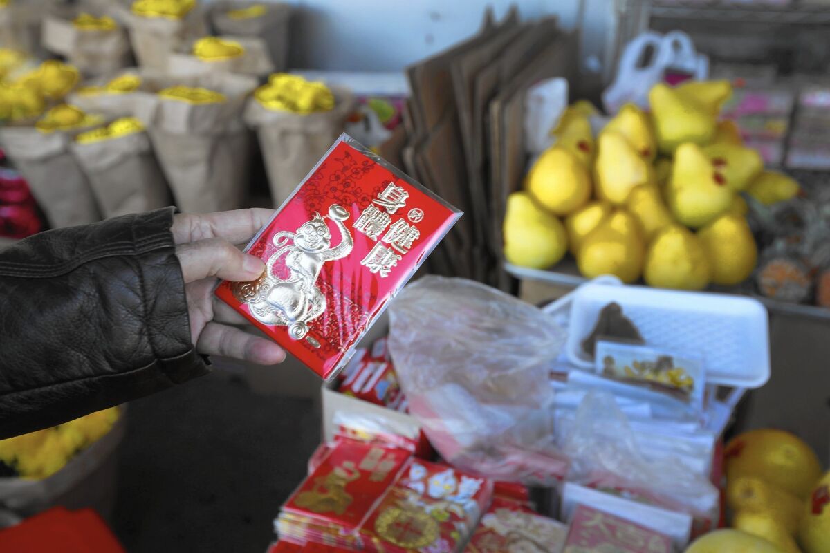 Thomas Le of San Diego buys a supply of red envelopes he'll use to put gift money into for the Lunar New Year. Throngs of shoppers were in Westminster preparing for the Feb. 8 celebration.