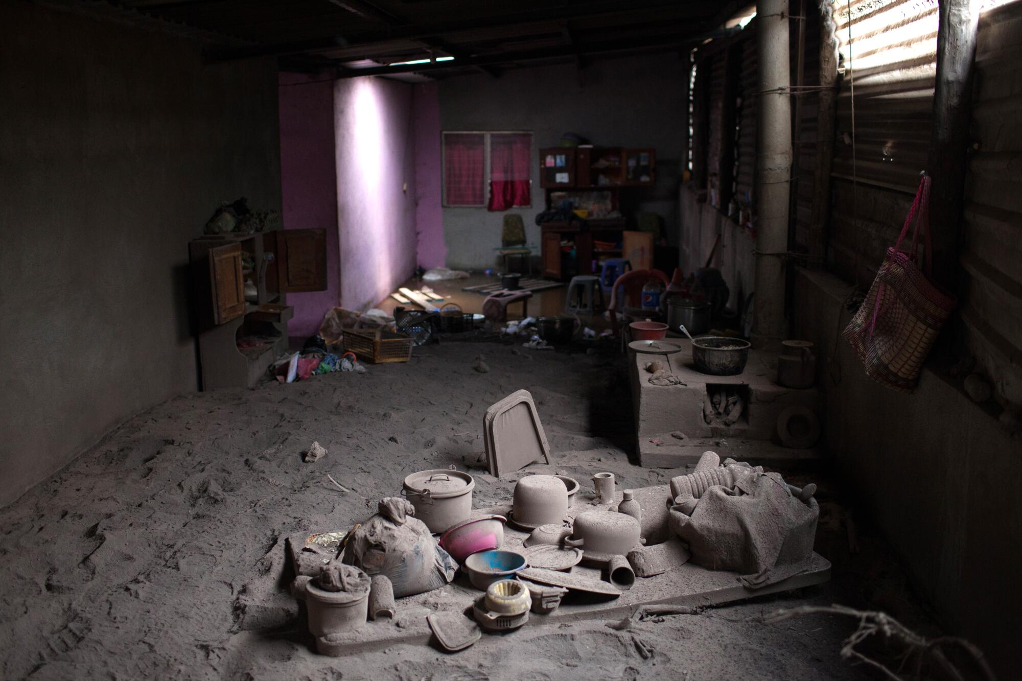 Utensilios de cocina cubiertos de ceniza sobre una mesa de comedor enterrada entre los escombros volcánicos dentro de una casa en la comunidad de San Miguel los Lotes.