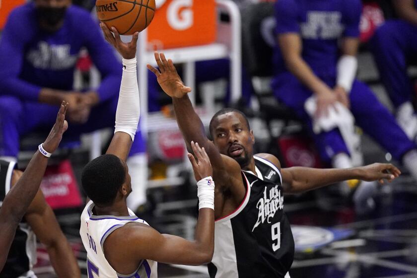 Sacramento Kings guard De'Aaron Fox, left, shoots as Los Angeles Clippers center Serge Ibaka.
