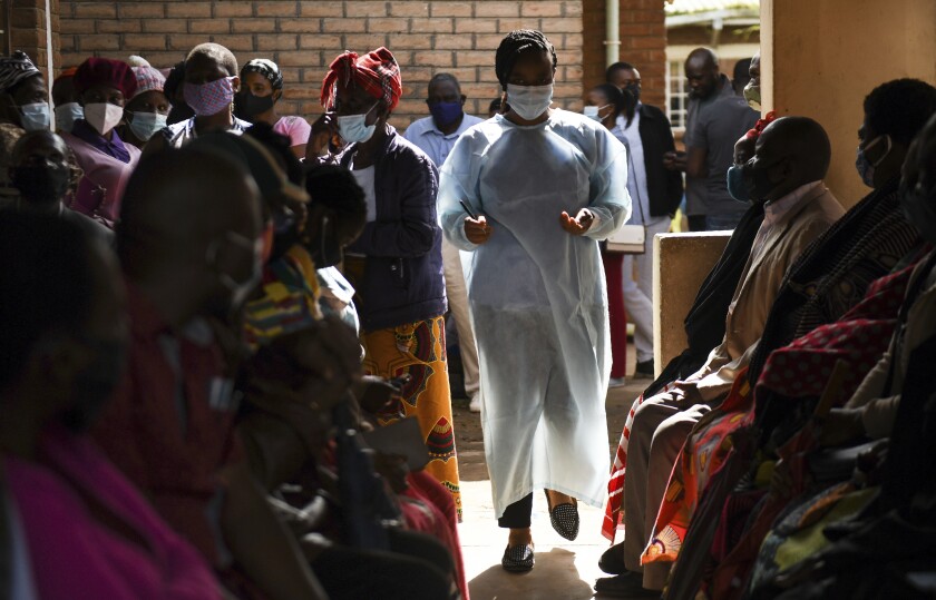 Numbers are handed out to people who wait to receive the AstraZeneca COVID-19 vaccine at Ndirande Health Centre in Blantyre Malawi, Monday, March 29, 2021. Malawi is vaccinating health care workers, elderly and those with health conditions that put them at higher risk of severe COVID-19, using the AstraZeneca doses that arrived early in March. (AP Photo/Thoko Chikondi)