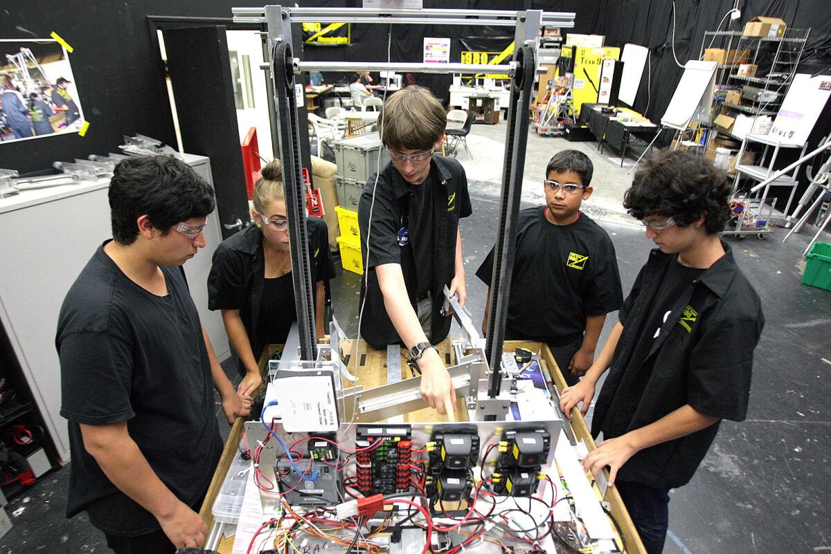 Ryan Aguiar, 17, of Burbank, Kaitlyn Waldman, 17, of Granada Hills, Andrew Farrow, 16, of Sunland-Tujunga, Jairo Estrada, 14, of Burbank, Issac Ehring, 14, of Burbank with FRC Team 980 ThunderBots work together to figure out how to attach an arm that will gather and lift crates at one of the team's regular Tuesday night gatherings in space provided by Disney in Glendale on Tuesday, September 15, 2015. The program is the only FIRST Robotics team for area students not connected to a high school.