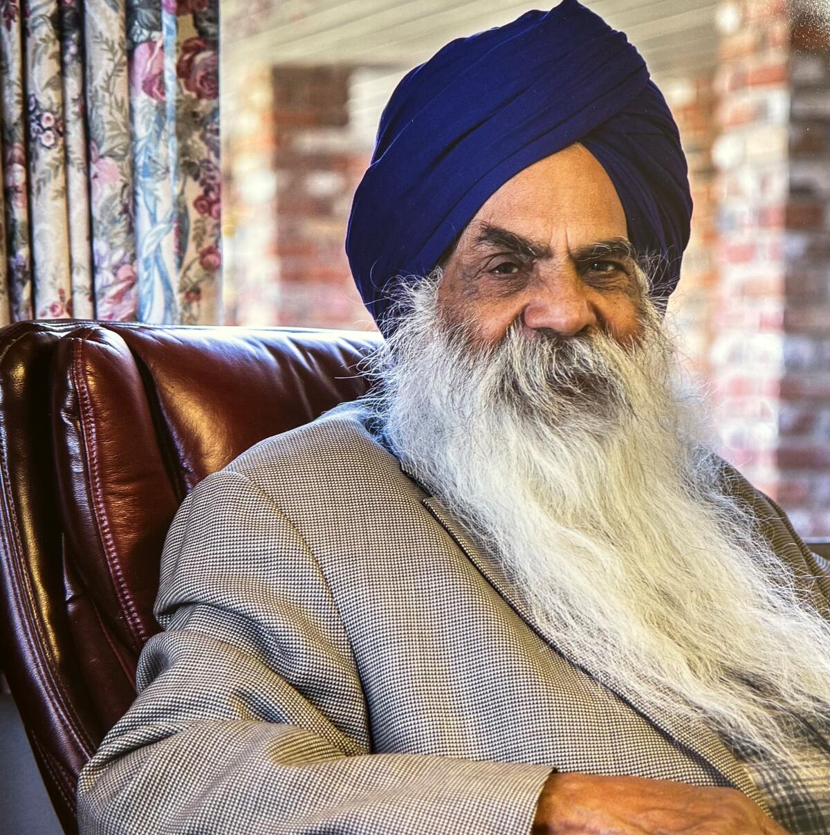 Portrait of a man with a long flowing beard and turban sitting in a chair