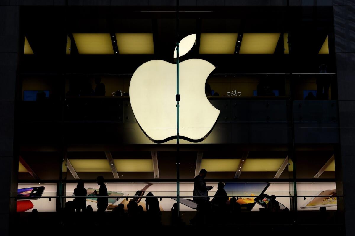 Customers are silhouetted inside of an Apple store in Sydney, Australia.