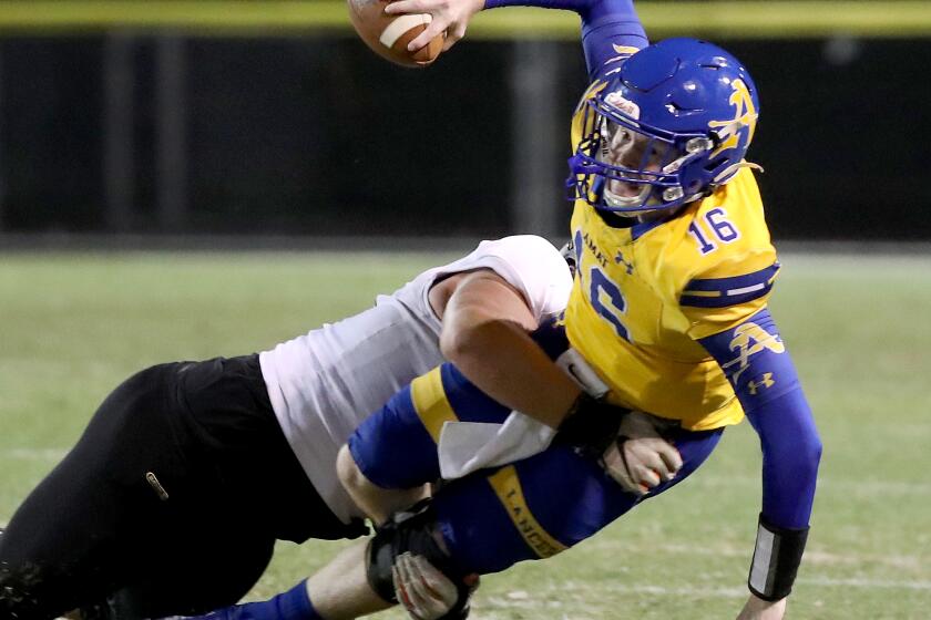 LA PUENTE, CALIF. - SEP 9, 2021. Bishop Amat quarterback Tobin O'Dell is brought down for a loss by Servite defensive tackle Mason Graham on Thursday night, Sep. 9, 2021. (Luis Sinco / Los Angeles Times)