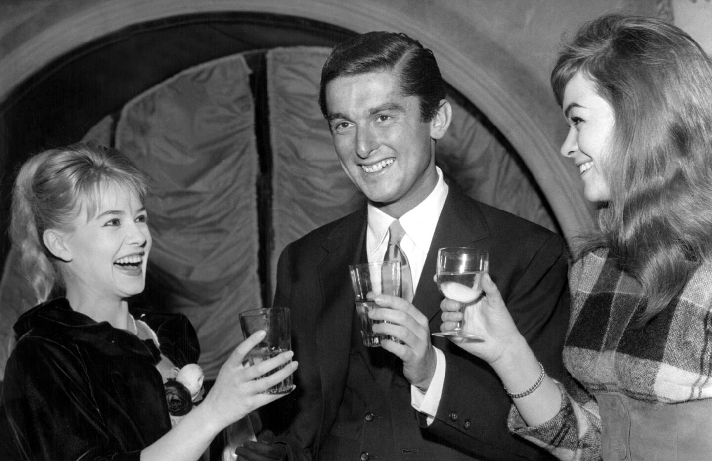 Robert Evans, center, with Sophie Daumier, left, And Marie Versini at a coctial party at a Paris restaurant on December 3. 1959.