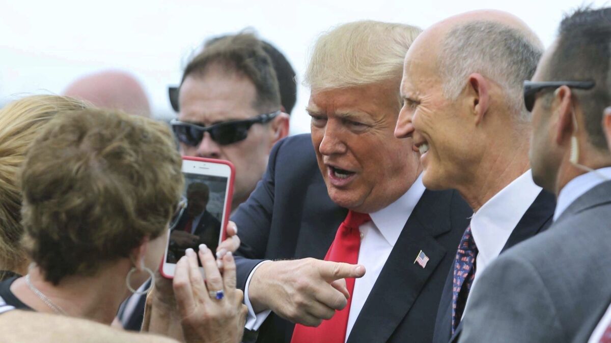 Florida Gov. Rick Scott, right, welcomes President Trump at Orlando International Airport on Monday. Scott is challenging U.S. Sen. Bill Nelson in next month's election.