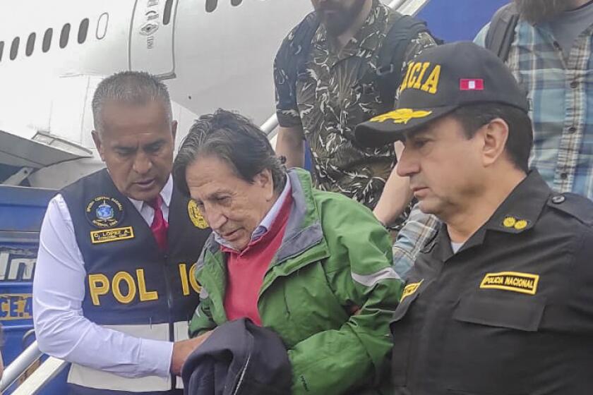 Officers escort former President Alejandro Toledo upon his arrival from the United States to the airport in Lima.