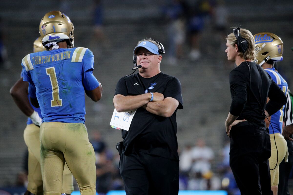 UCLA coach Chip Kelly, joined by quarterback Dorian Thompson-Robinson, stares at the scoreboard