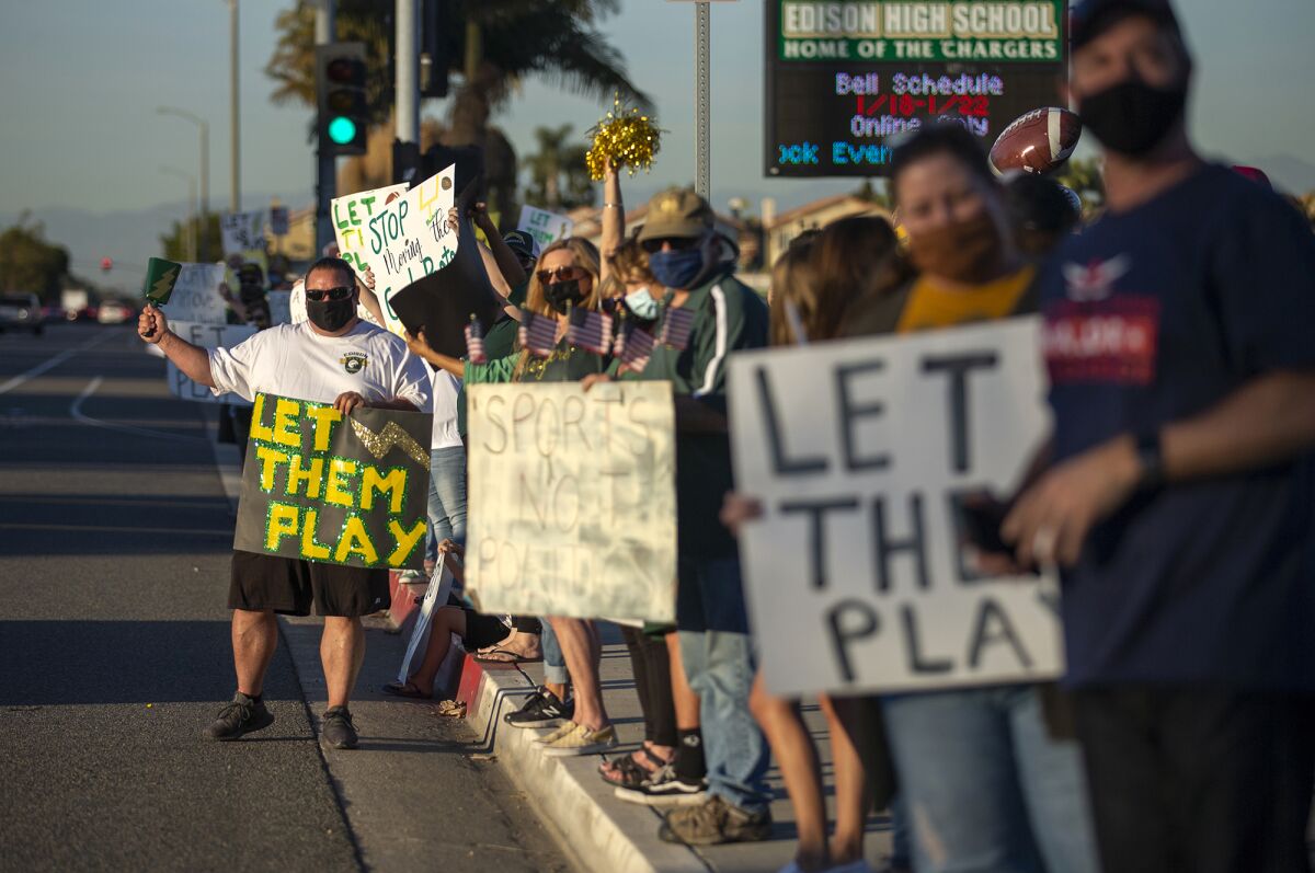 Mike Pino, left, and others participate in a "Let Them Play" rally at Edison High School on Friday.