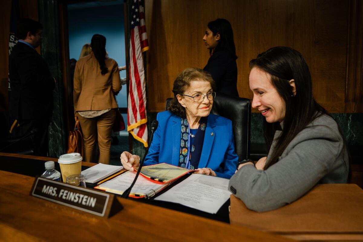 Sen. Dianne Feinstein and an aide seated at the dais