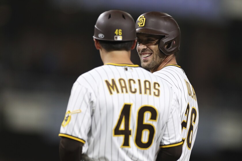 San Diego Padres' Austin Nola smiles next to first base coach David Macias after hitting an RBI single against the Philadelphia Phillies during the sixth inning of a baseball game Friday, June 24, 2022, in San Diego. (AP Photo/Derrick Tuskan)