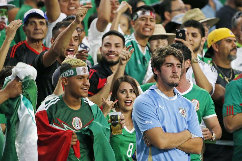A dejected Uruguay fan, right, is surrounded by cheering Mexico fans after a third Mexico goal during the second half of a Copa America group C soccer match at University of Phoenix Stadium Sunday, June 5, 2016, in Glendale, Ariz. Mexico defeated Uruguay 3-1. (AP Photo/Ross D. Franklin)