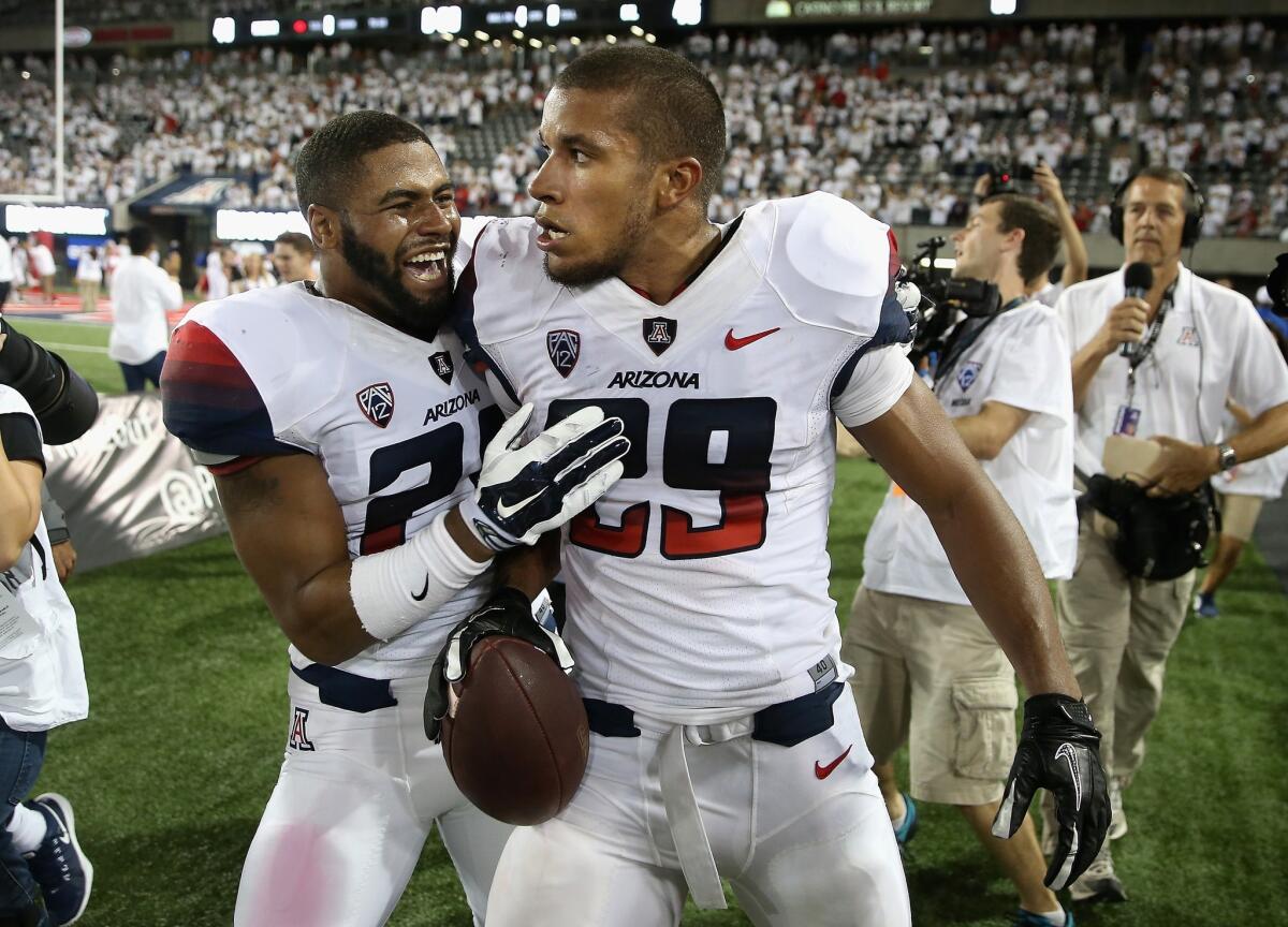 Arizona wideout Austin Hill is congratulated by teammate Nick Wilson after catching the game-winning 47-yard touchdown on Saturday night in Tucson, Ariz. The Wildcats beat the Golden Bears, 49-45.