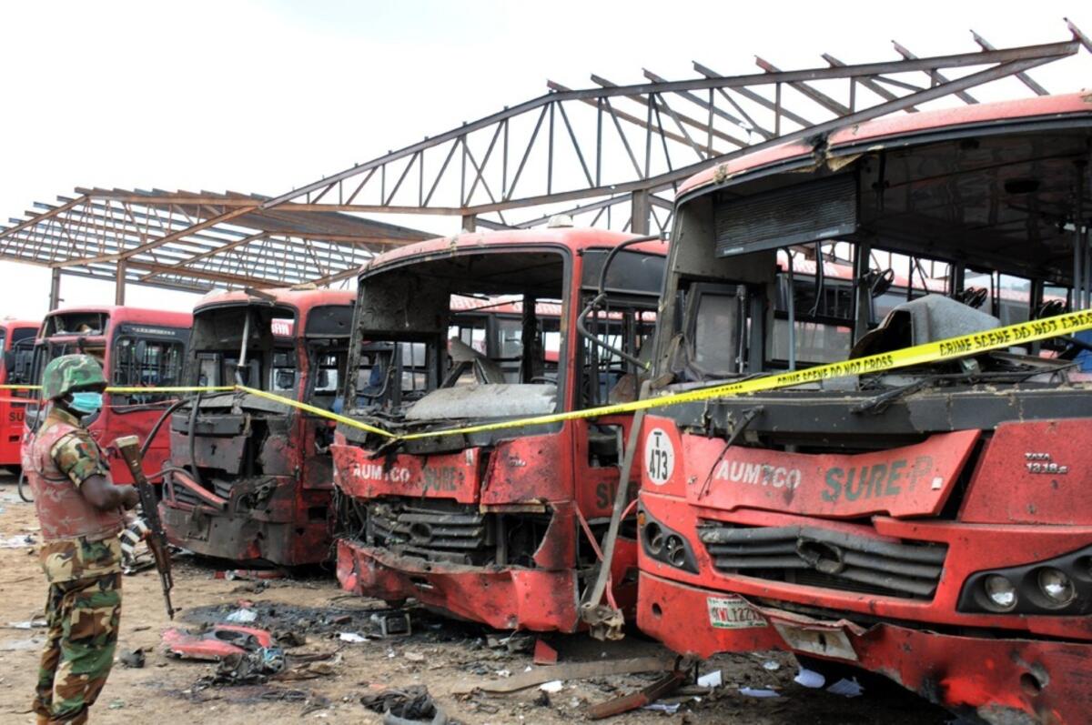 A soldier stands guard in front of burnt buses after an explosion outside the Nigerian capital, Abuja.