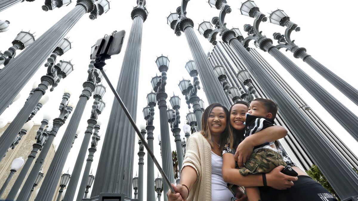 Marjorie Mabini, left, takes a selfie with her niece Jaydah Mabini, and son Jaren, 1, in front of the "Urban Light" installation at the Los Angeles County Museum of Art in Los Angeles. They are visiting from Oahu, Hawaii.