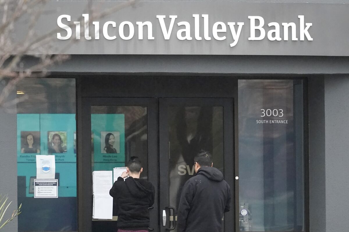 People look at signs posted outside of an entrance to Silicon Valley Bank in Santa Clara on March 10.