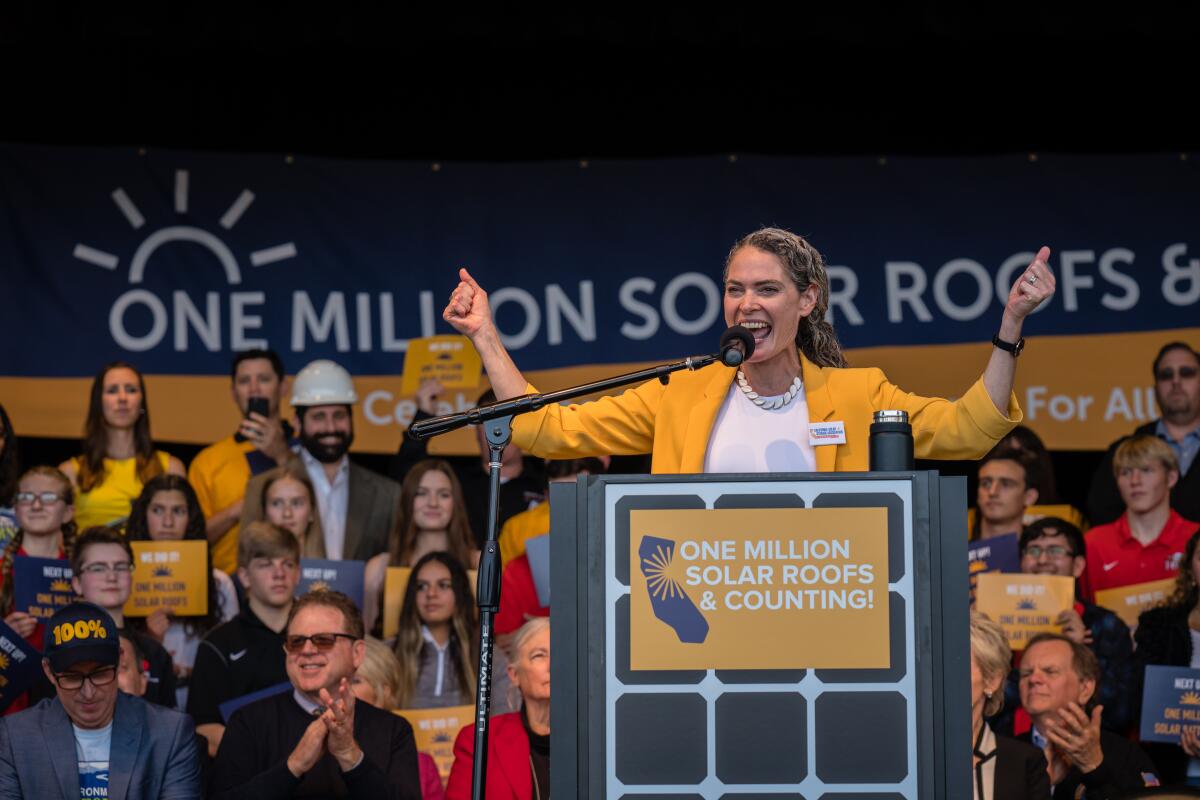 A woman speaks in front of a crowd. 