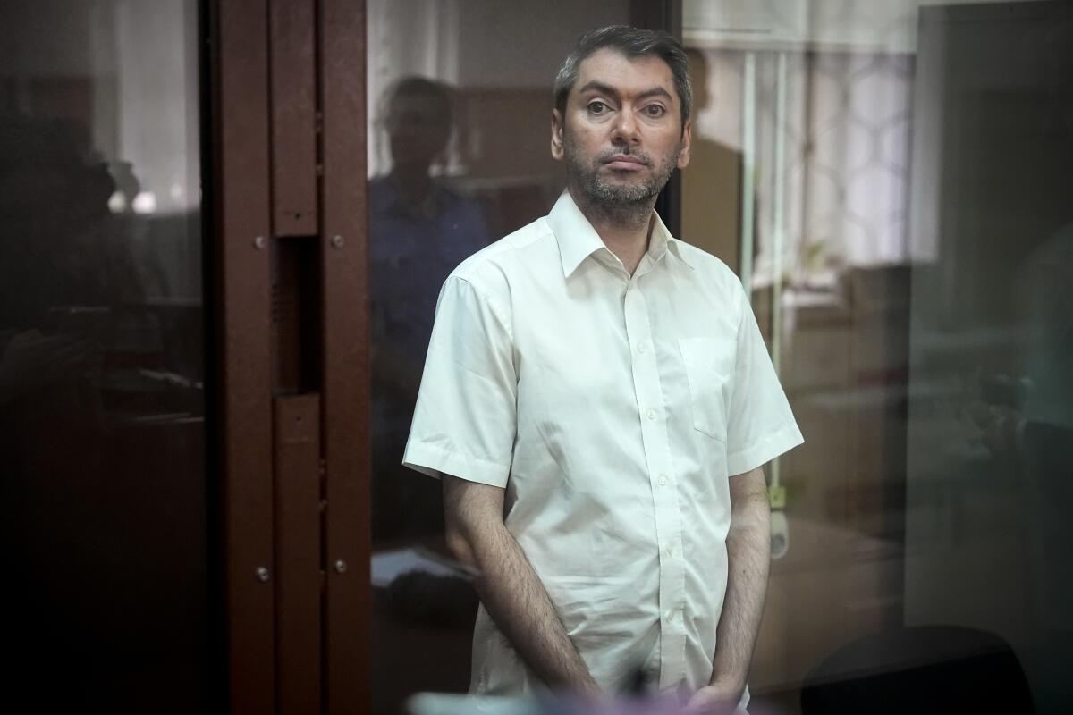 Grigory Melkonyants, a prominent Russian election monitor, stands in a cage behind glass in court.